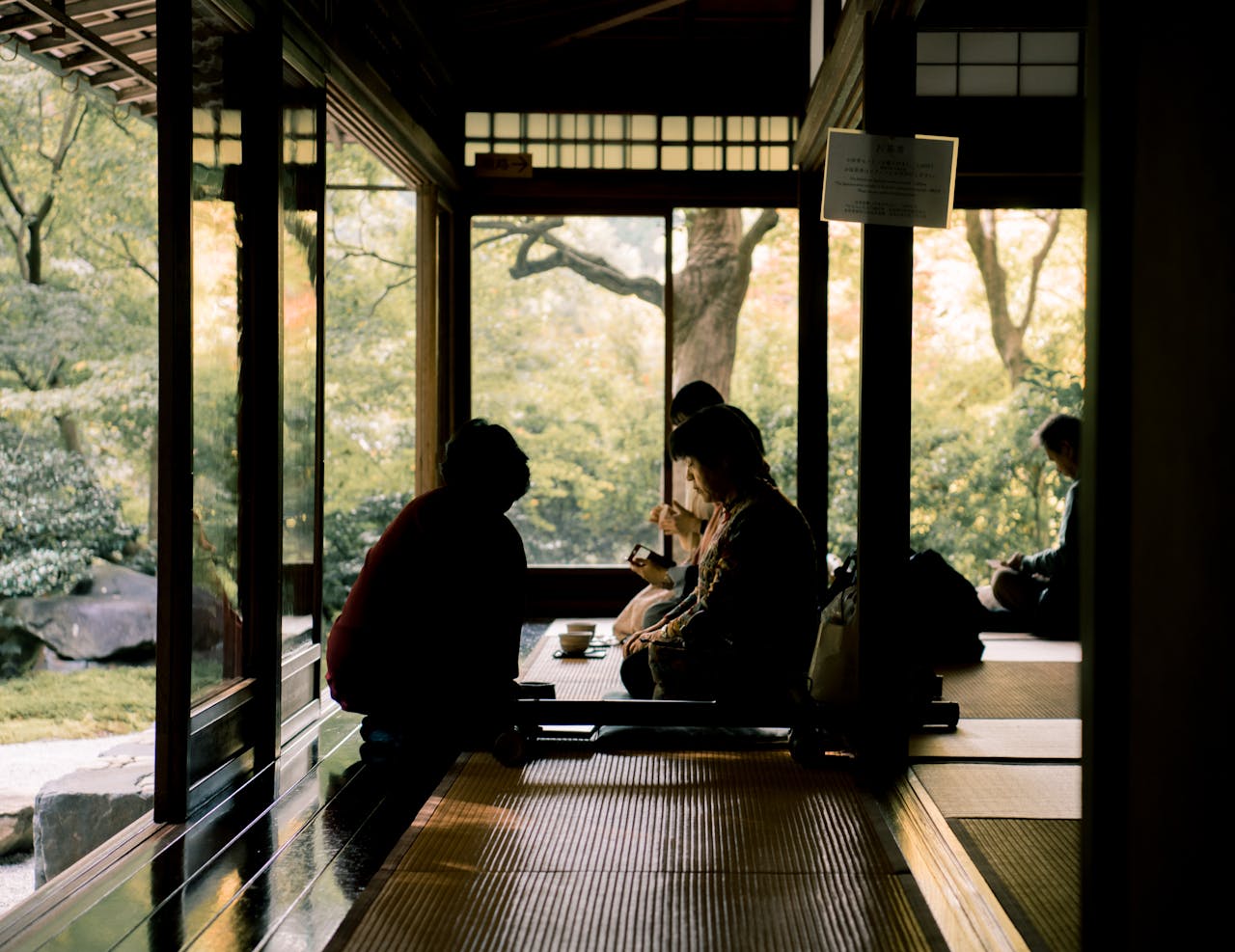 Group enjoying a serene tea experience in a Kyoto tea room overlooking a lush garden.
