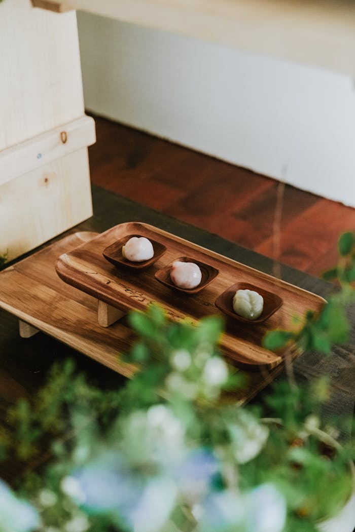Three mochi desserts presented on a wooden tray with a rustic and elegant setting.