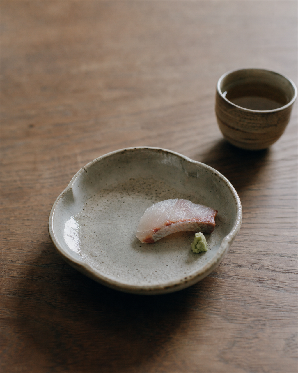A small kaiseki dish with a single carefully arranged seasonal ingredient on a ceramic plate