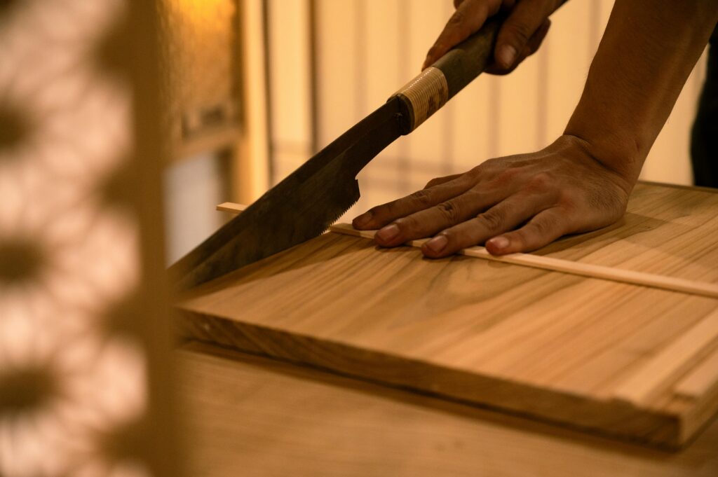 Close-up of a hand using a traditional saw to cut wood precisely. Perfect for woodworking themes.