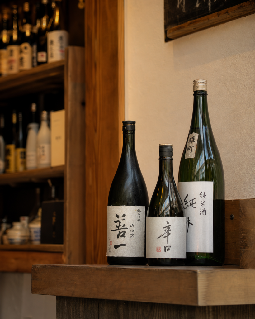 Japanese sake bottles on a wooden shelf at a sake shop or izakaya