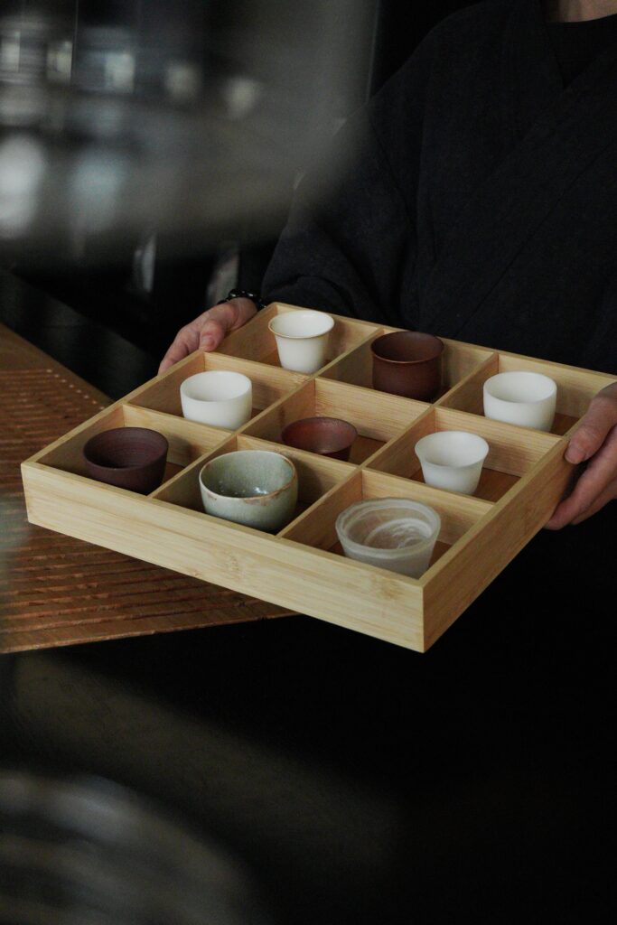 Artistic display of ceramic cups in a wooden tray in Ho Chi Minh City.
