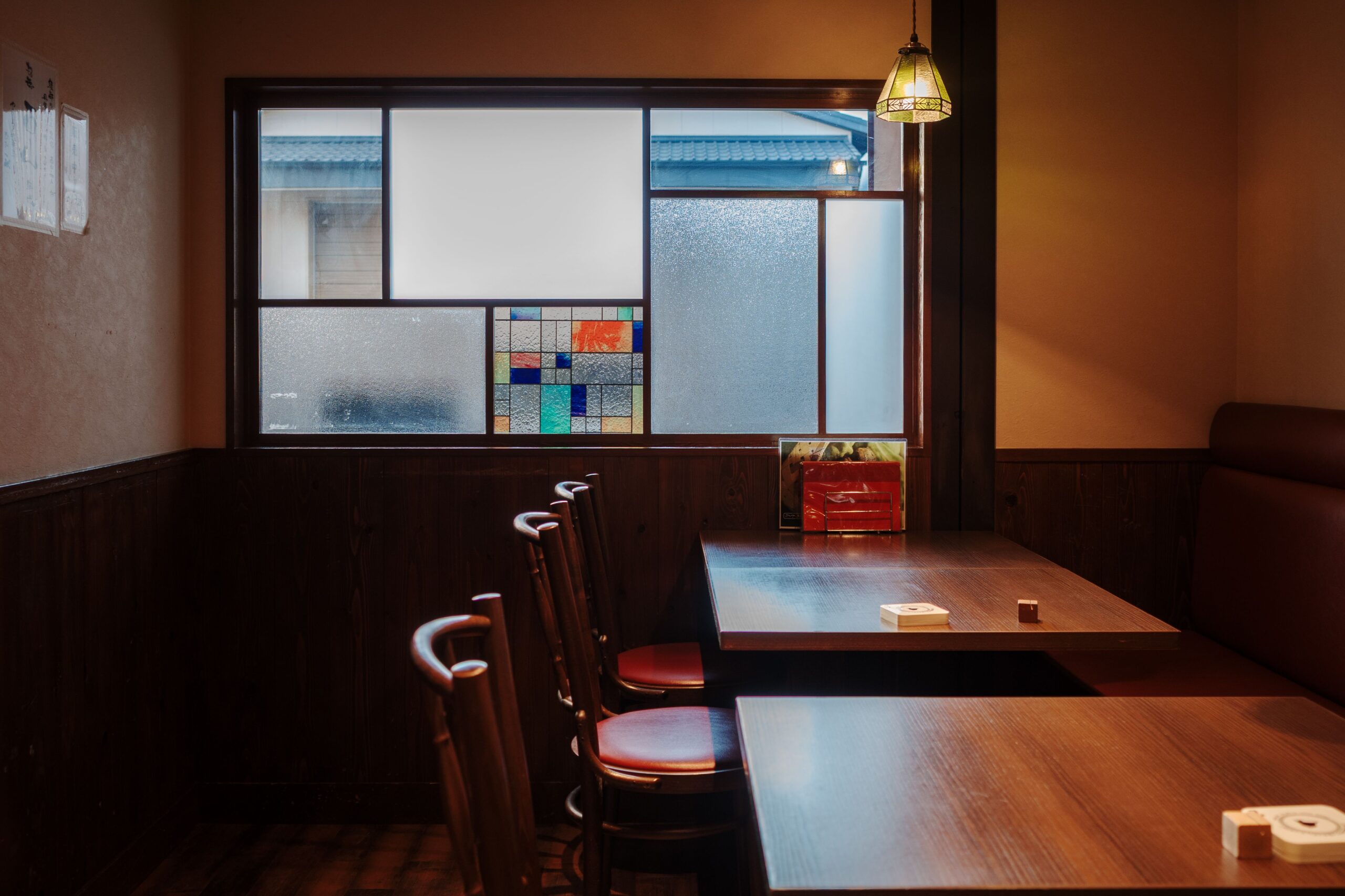 Warm and inviting Kyoto café interior featuring wooden furniture and stained glass detail.