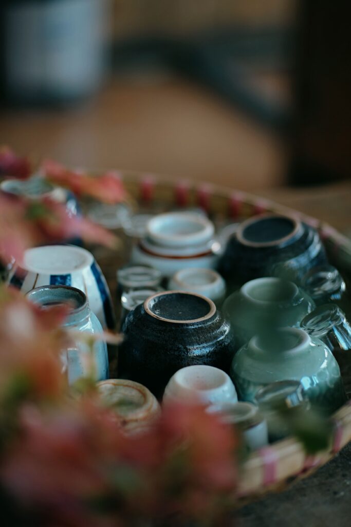 A curated collection of upside down ceramic cups in various colors and textures on a wicker tray.